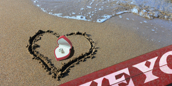 浜辺に書いたハートの中に置かれた婚約指輪